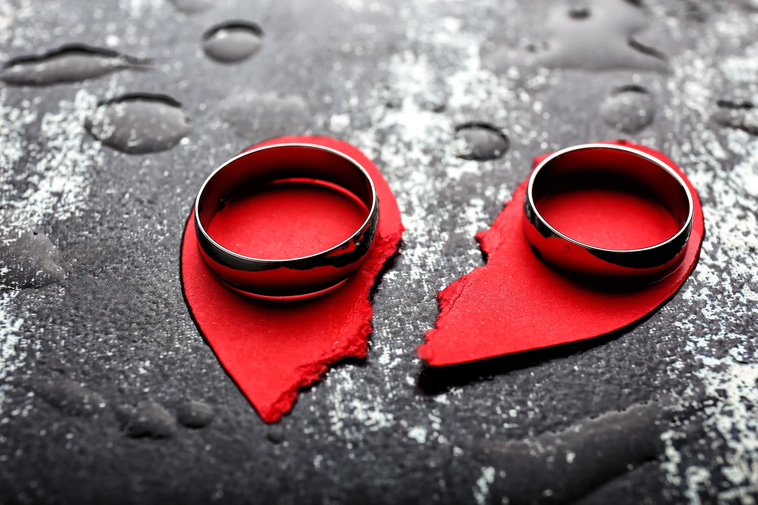 Broken heart and rings on grunge background. Concept of divorce